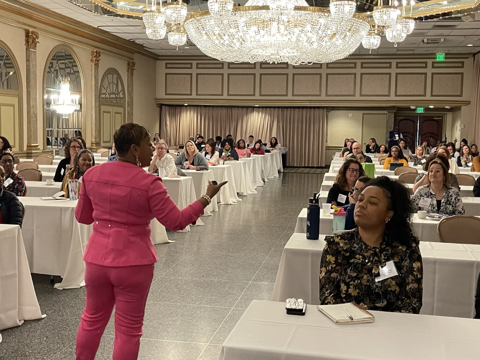 Kelly Charles-Collins, Esq. presenting to a ballroom conference audience